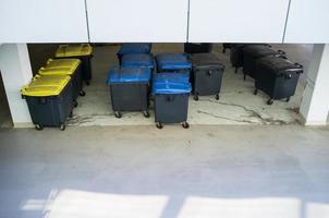 Many plastic garbage containers stand near the building, on the city street. Top view. photo