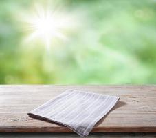 White napkin, table cloth on wooden deck mockup. Summer landscape background photo