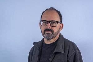 Portrait of 60 years old bearded man on blue background with hat and glasses photo