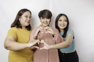 tres mujeres asiáticas se sienten felices y un gesto de corazón de formas románticas expresa sentimientos tiernos, concepto de amistad cercana. foto