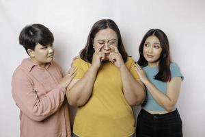 A portrait of three friends looking sad crying wiped her tears and hug each other, isolated white background photo