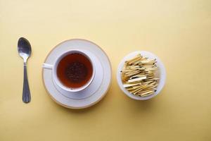 artificial sweetener powder in a packet and cup of tea on yellow background photo