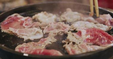 use palillos para asar el cerdo en una sartén caliente. video