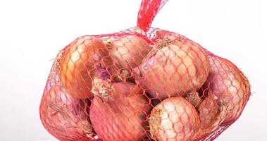 Close-up of shallots gathered in a mesh bag on a table. video