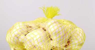 Close-up of large cloves of garlic gathered in mesh bags on a table. video