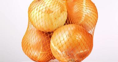 Close-up of onions gathered in a mesh bag on a table. video