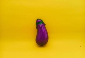 plastic toy in the form of eggplant or with the Latin name Solanum melongena on a yellow background isolated photo