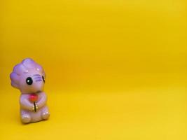 Purple dinosaur - shaped plastic toys with an isolated yellow background photo