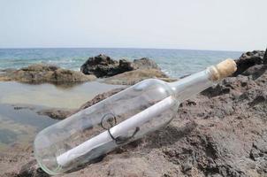 botella de vidrio en la arena foto