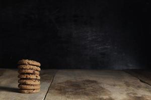 stack of chocolate cookies on wooden table on black background photo