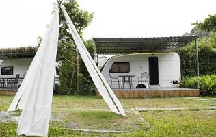 Triangular wooden tents decorated with white cloth with Caravan trailer background photo