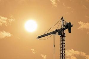 Silhouettes of tower construction cranes with yellow sky at morning time photo