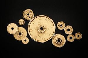 pile of golden gears on black background photo