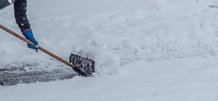 Young man shoveling snow from the walking path in winter. photo