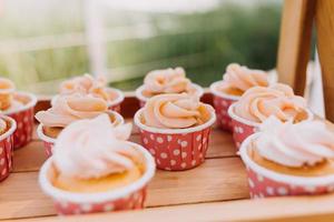 Gourmet cupcakes with white buttercream frosting and sprinkles on wooden background photo