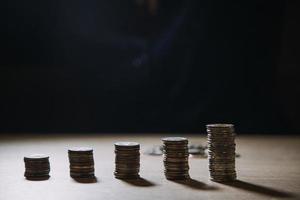 ahorrar dinero a mano poniendo monedas en la pila en la mesa con sol. concepto finanzas y contabilidad foto