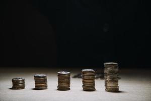 ahorrar dinero a mano poniendo monedas en la pila en la mesa con sol. concepto finanzas y contabilidad foto