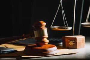 Business and lawyers discussing contract papers with brass scale on desk in office. Law, legal services, advice, justice and law concept photo