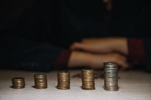 saving money hand putting coins on stack on table with sunshine. concept finance and accounting photo