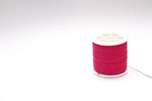 The red thread spool is placed on a white background. photo