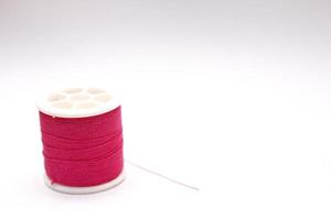 The red thread spool is placed on a white background. photo