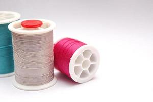 Green, red, colored thread spools placed on a white background. photo