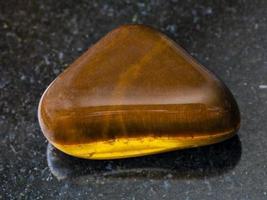 tumbled tiger-eye gem stone on dark background photo