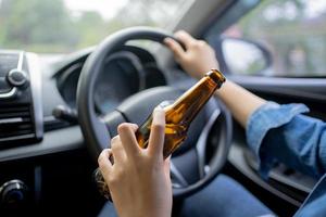 Young woman drinking beer while driving Risk of accidents due to drunk driving photo