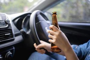mujer bebiendo de una botella de cerveza mientras conduce un camión, un concepto de conducir intoxicado.
