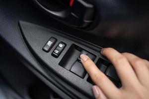 Hand pressing window buttons inside luxury car. Automatic power controlling system close-up view photo
