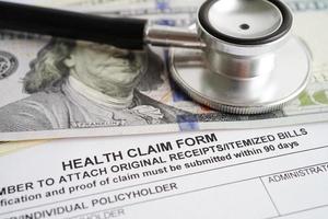 Health claim form with stethoscope and US dollar banknotes, insurance accident medical concept. photo