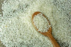dry rice or uncooked rice. top angle view of raw rice and wooden spoon photo