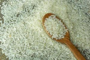 dry rice or uncooked rice. top angle view of raw rice and wooden spoon photo