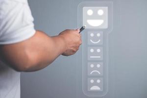 concepto de evaluación y satisfacción. alguien elige una emoción de sonrisa que es una excelente revisión con lápiz digital. el primer plano medio está sobre fondo gris con espacio de copia. foto