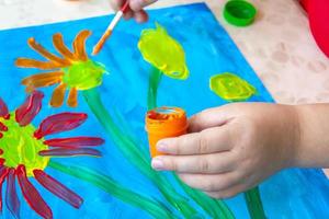 The child draws a bright picture. Large strokes of paint on paper. photo