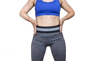 Fitness girl in a top and leggings points to her athletic figure. The Concept Of Weight Loss. Model on a white background. photo