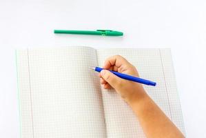 el niño sostiene sus manos sobre un cuaderno abierto y va a escribir en él. primer plano de las manos de un niño. foto