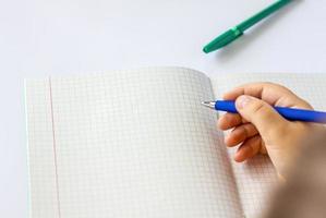 The child holds his hands over an open notebook and is going to write in it. Close-up of a child's hands. photo