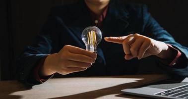 Businessman touching a bright light bulb. Concept of Ideas for presenting new ideas Great inspiration and innovation new beginning. photo