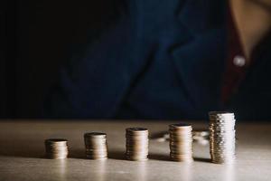 businesswoman hand puting coins in glass for saving money. concept finance and accounting photo