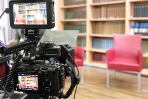 Two empty chairs in a TV studio with book panel in the background and camera in the foreground photo