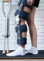 Female wearing knee orthosis or knee support brace after surgery on leg photo