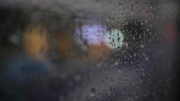 gota de água da tempestade de chuva na janela de vidro transparente dentro do ônibus enquanto preso na estrada na cidade com luz bokeh em 4k video