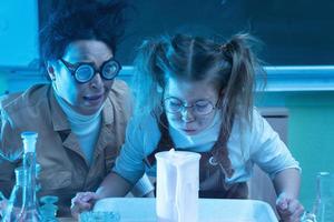 profesor y niña durante la lección de química mezclando productos químicos en un laboratorio foto