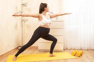 Pregnant woman during her yoga orkout at home photo