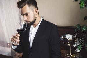 guapo hombre barbudo con una copa de vino tinto foto