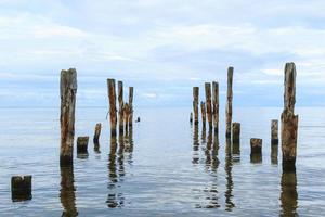 Sea scenery with broken pier poles sticking from water. photo