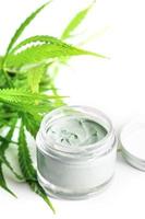 Green cannabis plant and jar with a moisturizing cream photo