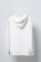 Blank white hoodie hanging on a hanger against gray background photo