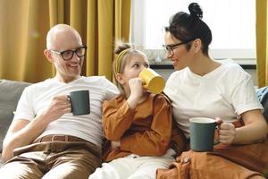 Happy family sitting on the sofa and drinking hot tea photo